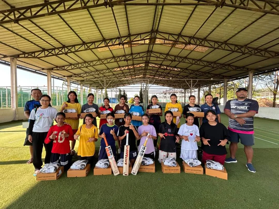 Women with cricket bats and equipment at an indoor practice facility