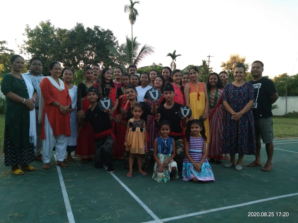 Children and adults gathered outdoors, including participants in traditional clothing